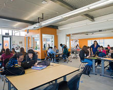 This photo shows students working in small groups in a typical paired classroom with the movable wall open. The teacher offices penetrate into the space to facilitate constant access between the students and faculty. - Photo Credit: Jim Brady Architectural Photography