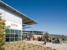 In the photo, students gather near the school entrance. Native landscaping can be seen in the foreground and background. - Photo Credit: Jim Brady Architectural Photography